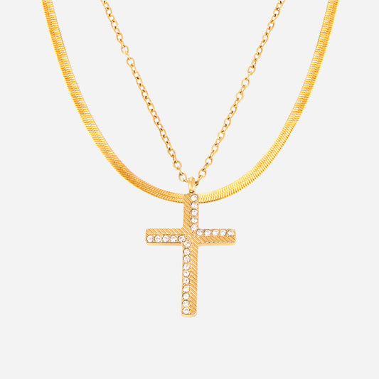 Gold necklace with a cross pendant on a light gray background