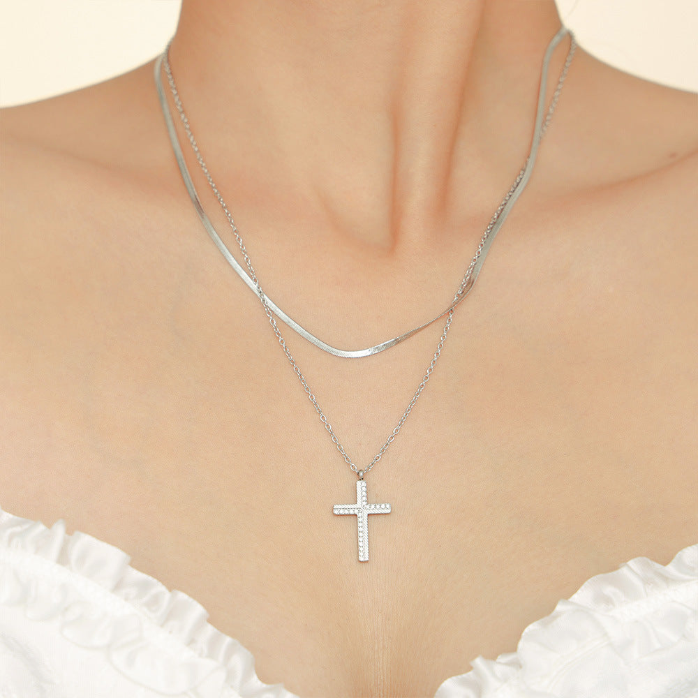 Silver cross necklace on a mannequin with a white top