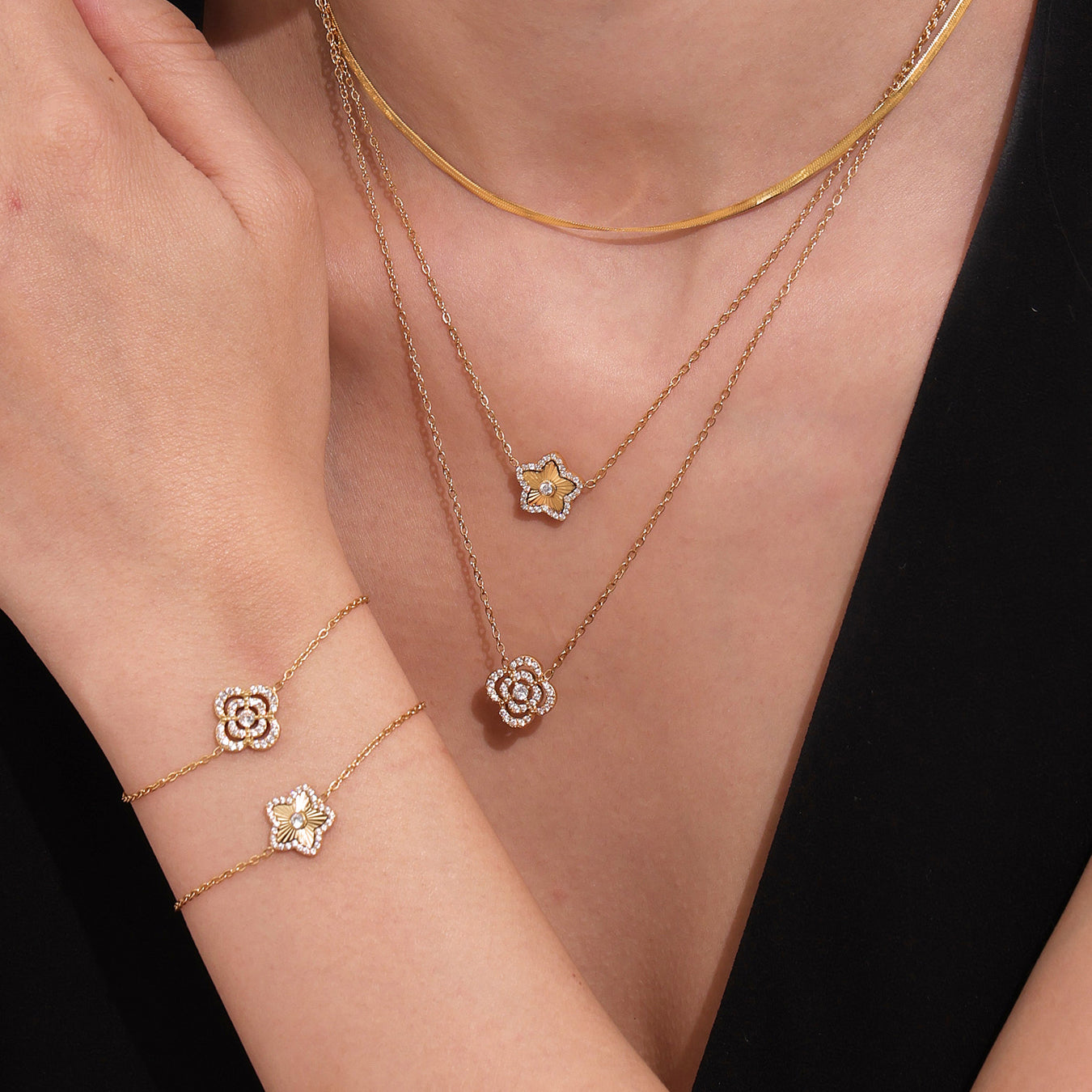 Gold necklaces with floral pendants on a person wearing a black top.