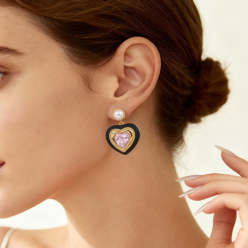 Close-up of gold heart earrings with pink gemstone and pearl detail worn by model, feminine romantic jewelry look