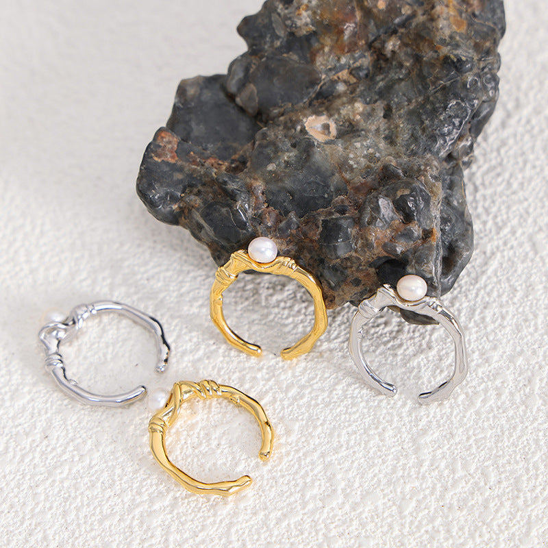 Three hoop earrings in gold and silver with pearls on a textured surface.