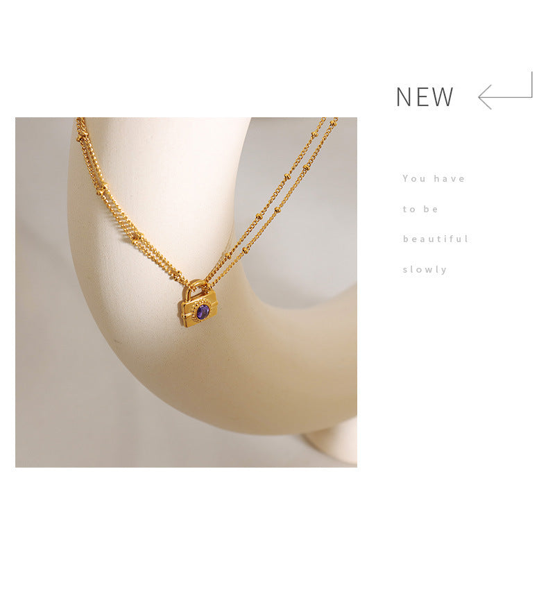 Gold necklace with a lock pendant on a mannequin bust against a white background