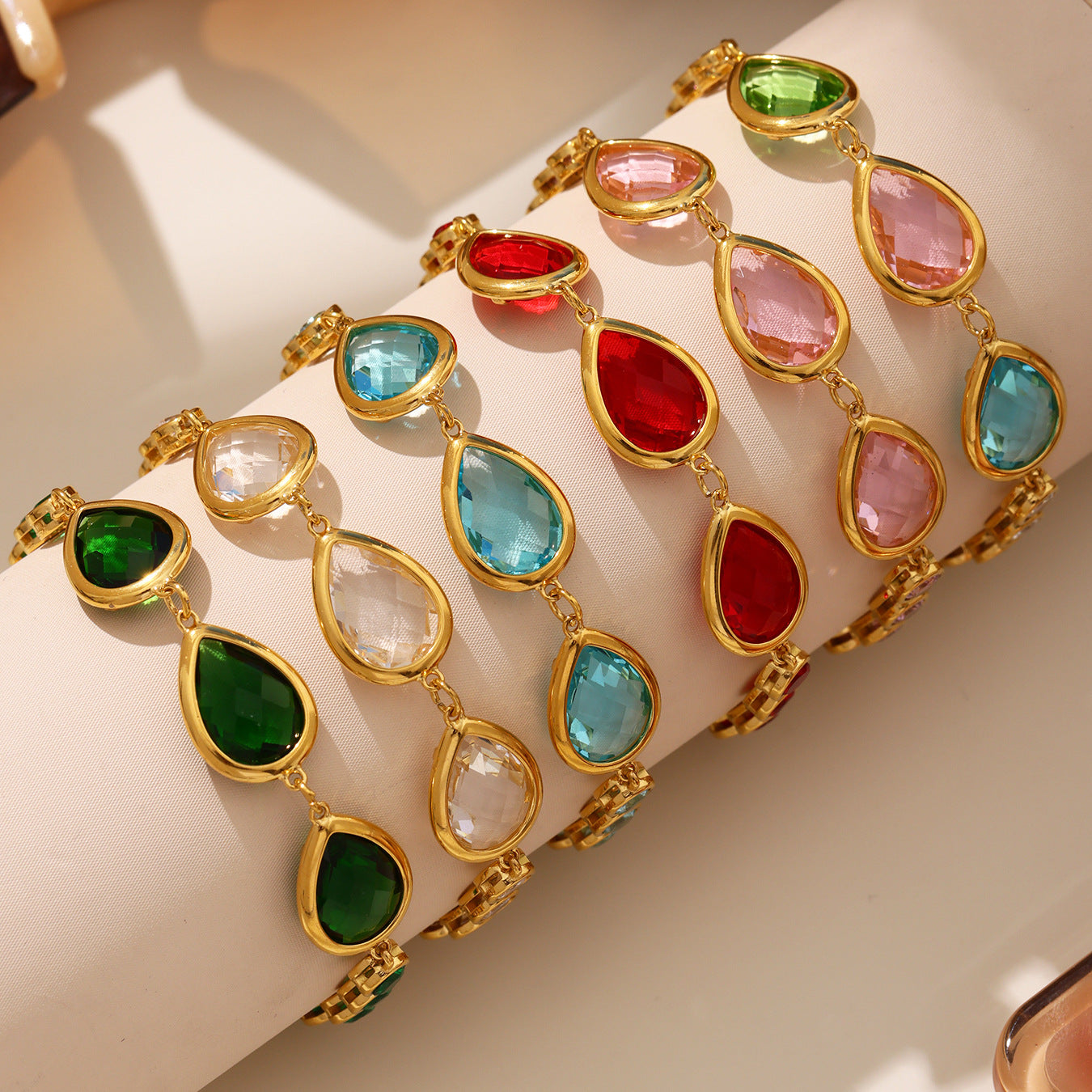 Close-up of colorful teardrop gemstones on gold bezel setting, sea glass bracelet details and shine