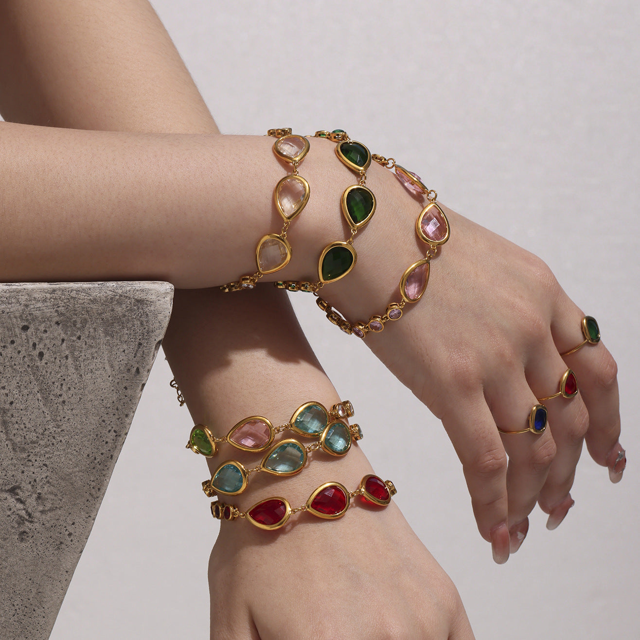 Arm lineup of sea glass teardrop bracelets with bezel crystal links, multiple colorways, gold stainless steel