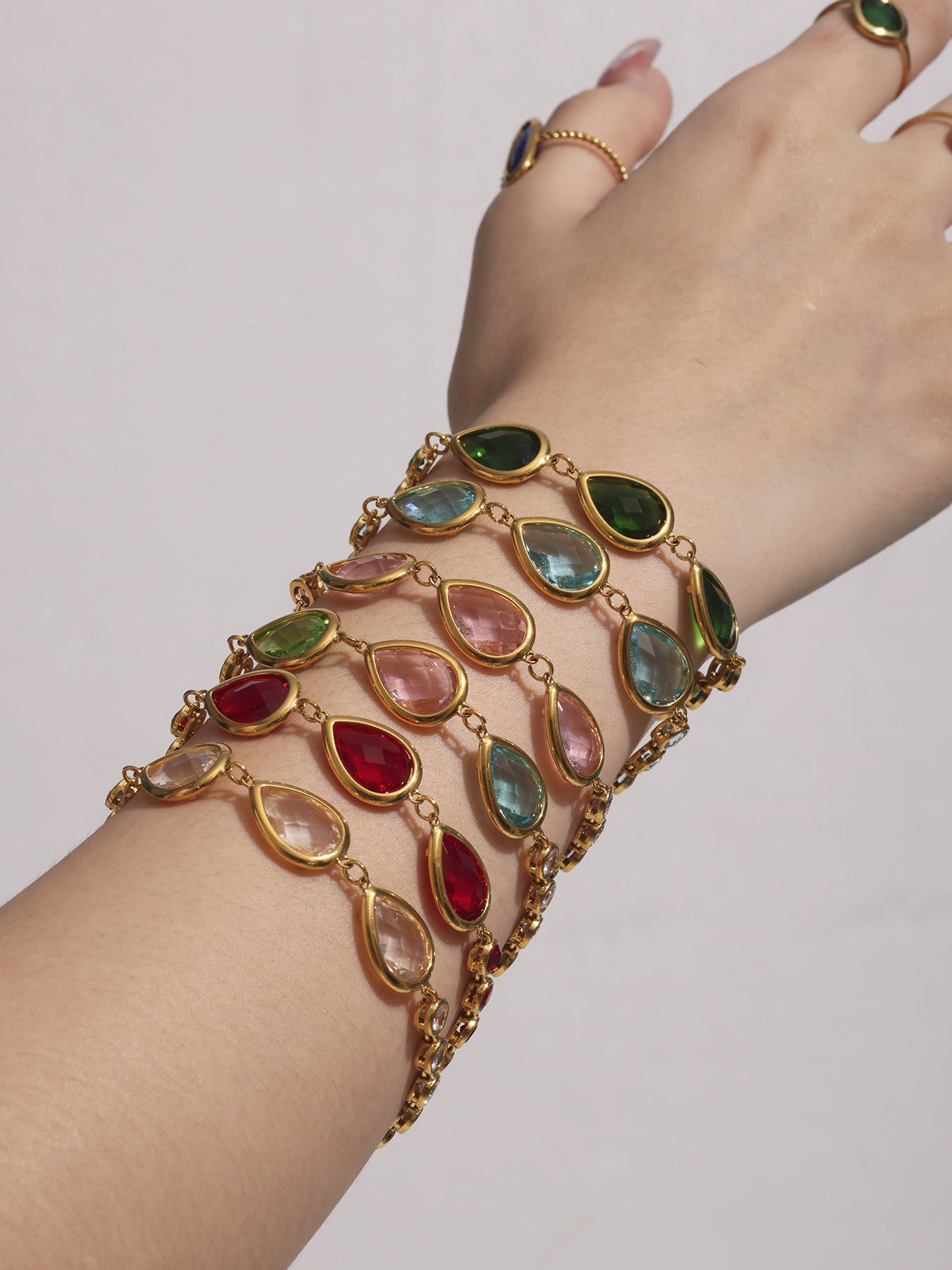 Stacked sea glass bracelets in pink, blue, green and red teardrops, dopamine color styling, gold stainless steel