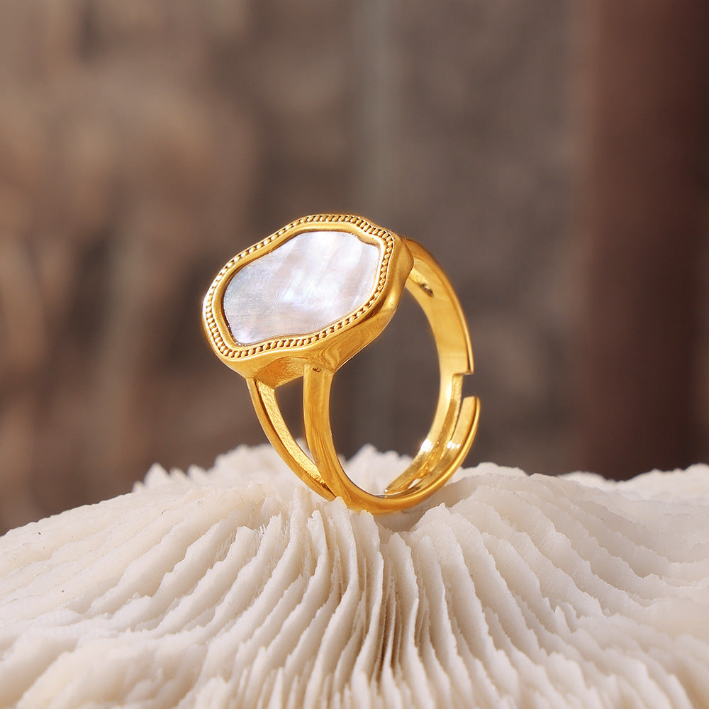 Gold stainless steel seashell ring with white mother of pearl on textured background