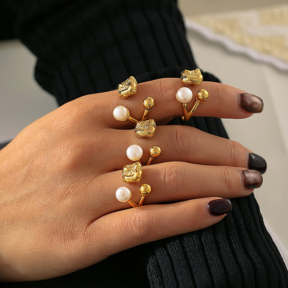 Hand wearing stacked gold and freshwater pearl rings for a layered fashion look against blurred background