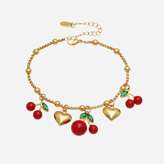 Gold bracelet with heart and cherry charms on a white background