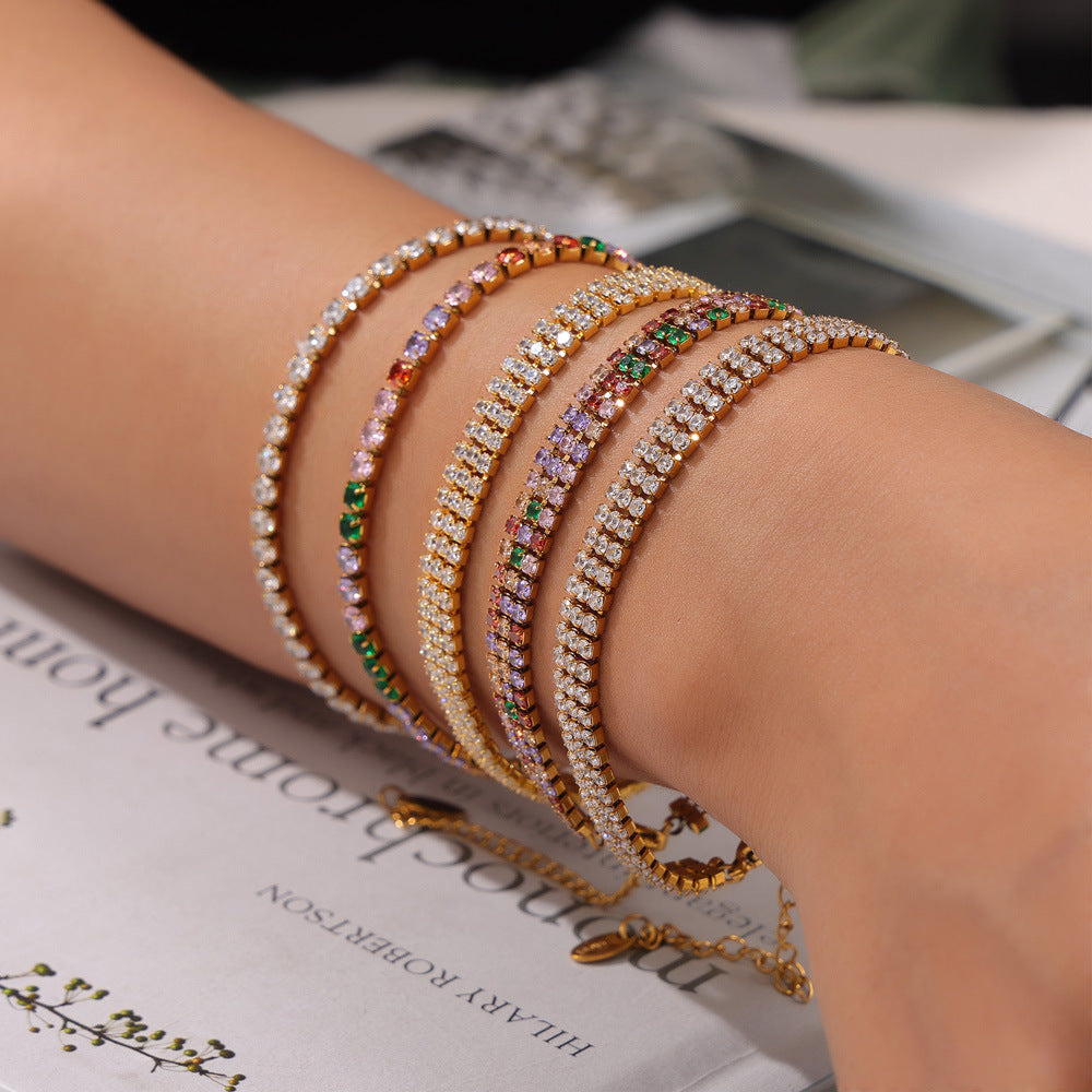 Multicolor zircon tennis bracelets styled on wrist – modern editorial look with newspaper background