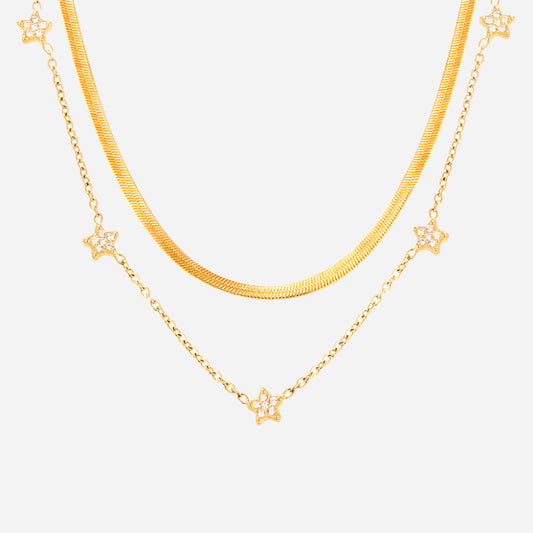 Gold five-pointed star tennis necklace and minimalist chain necklace folded on white background