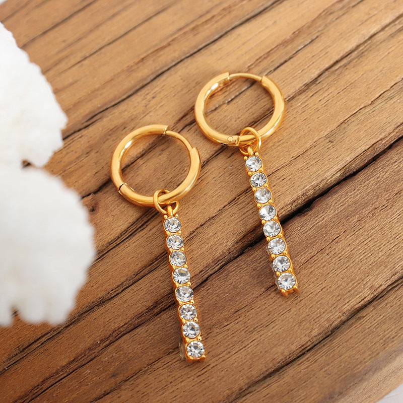 Gold crystal drop hoop earrings close-up on a wooden background showing elegant shine and minimalist style.
