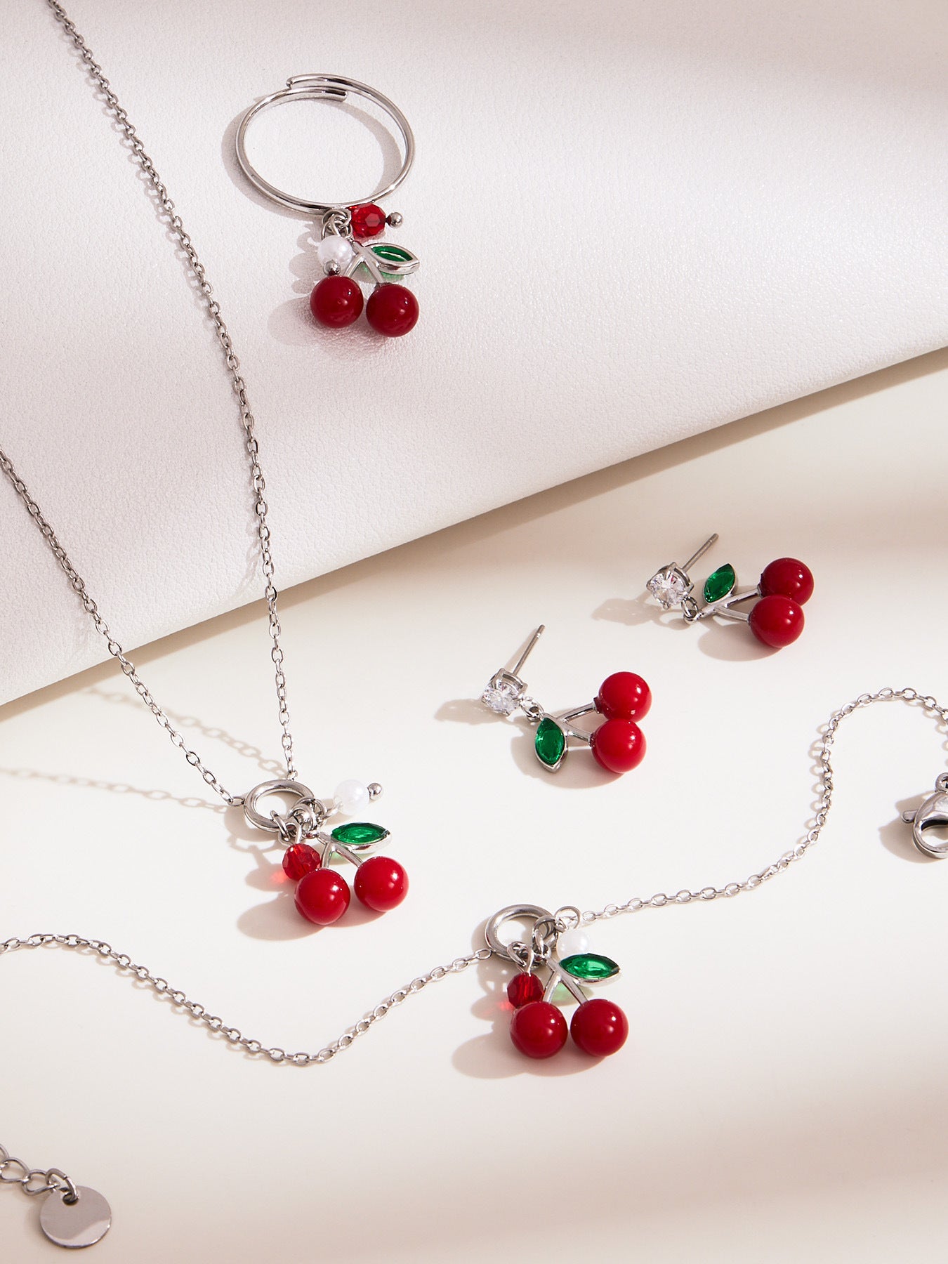 silver stainless steel cherry jewelry set with red cherry charms, pearl accents, and green enamel leaves, including necklace, ring, bracelet, and earrings